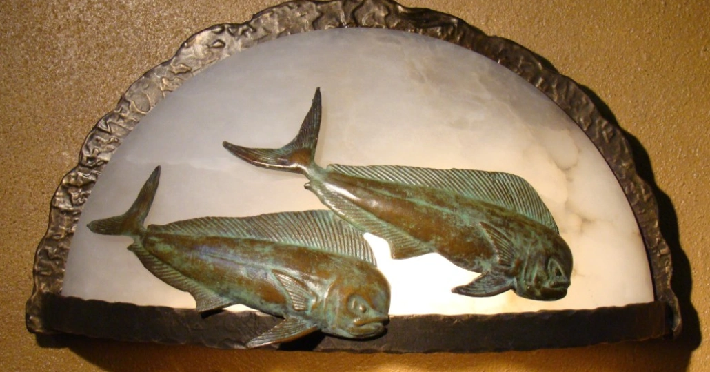 Two bronze fish on a plate with a white background