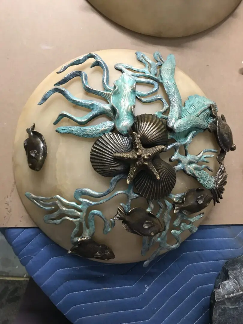 A round wall hanging with sea creatures on it.