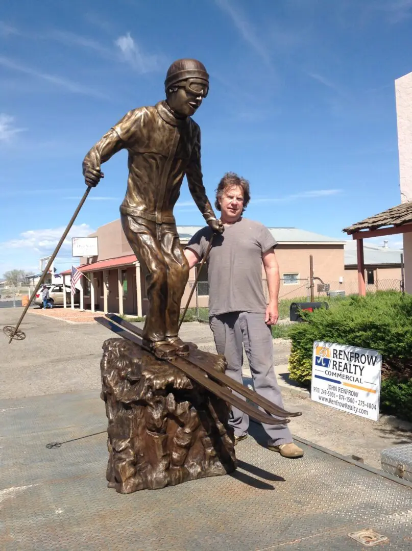 A man standing next to a statue of a skier.