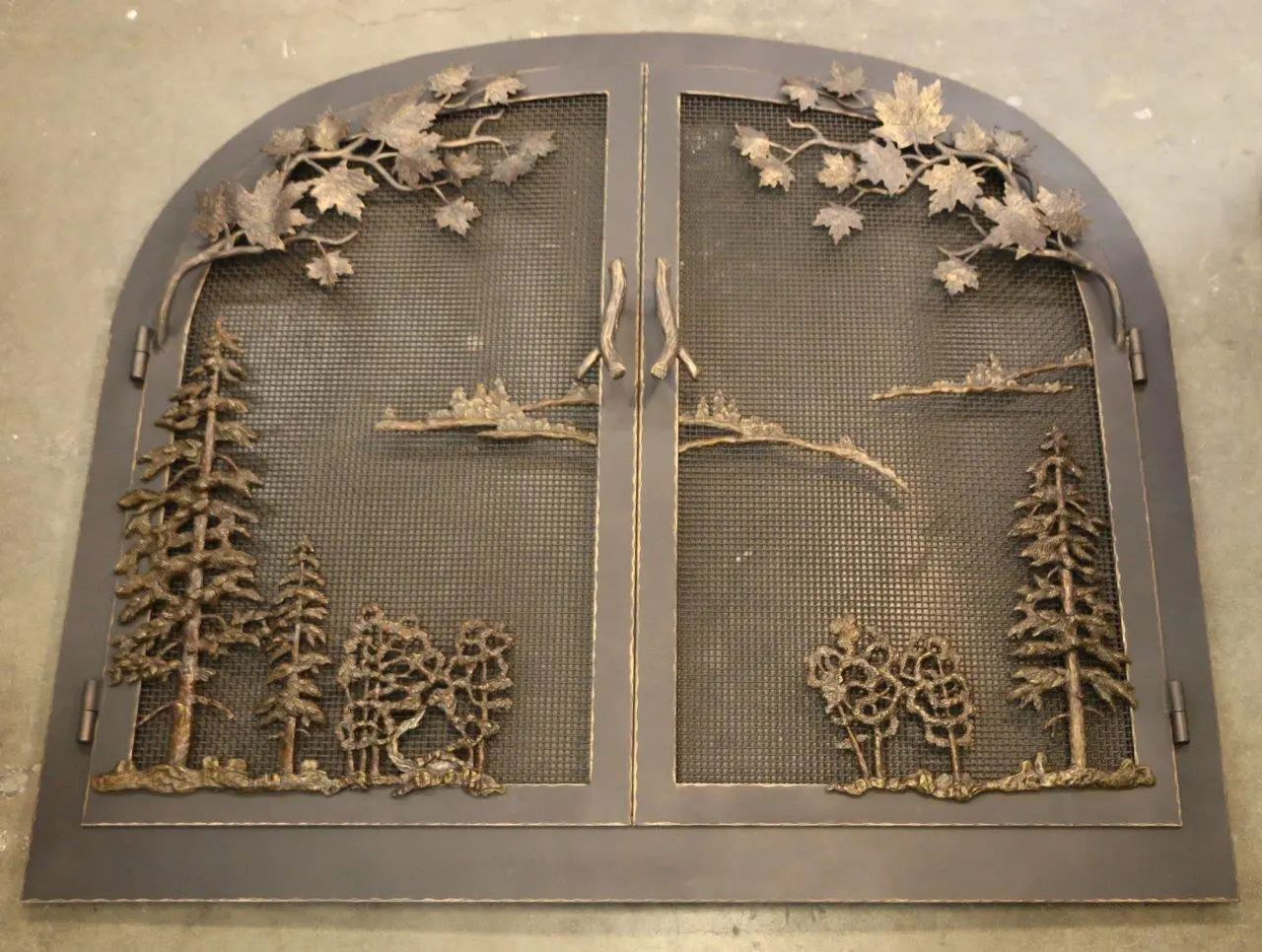 A metal door with trees and birds on it.