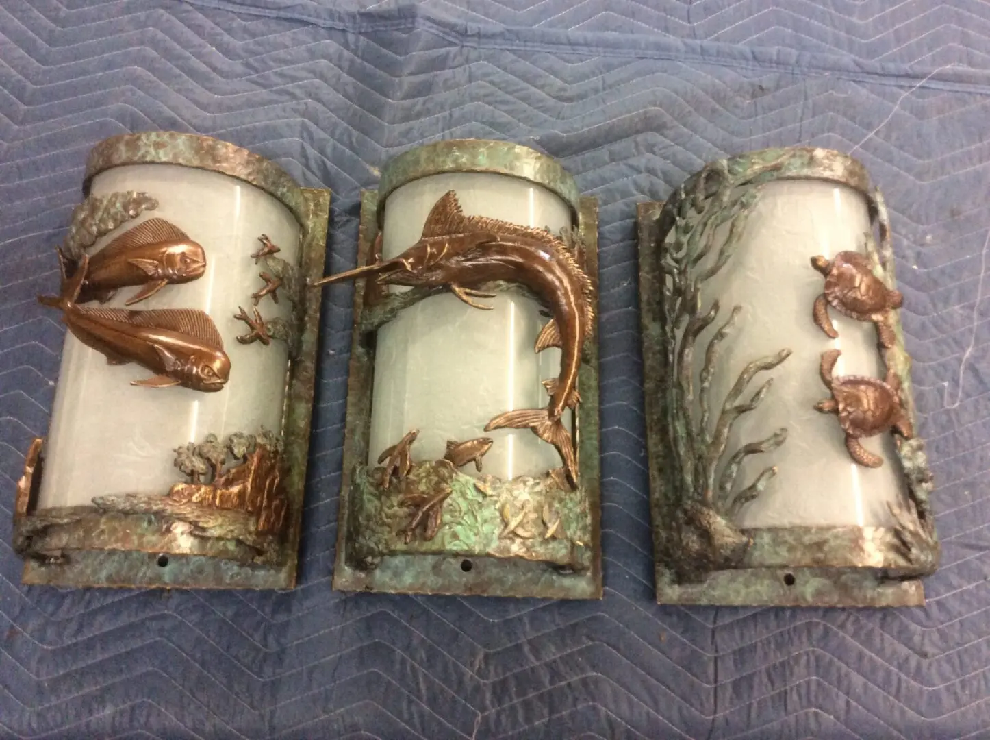 Three wall sconces with a fish and seaweed design.