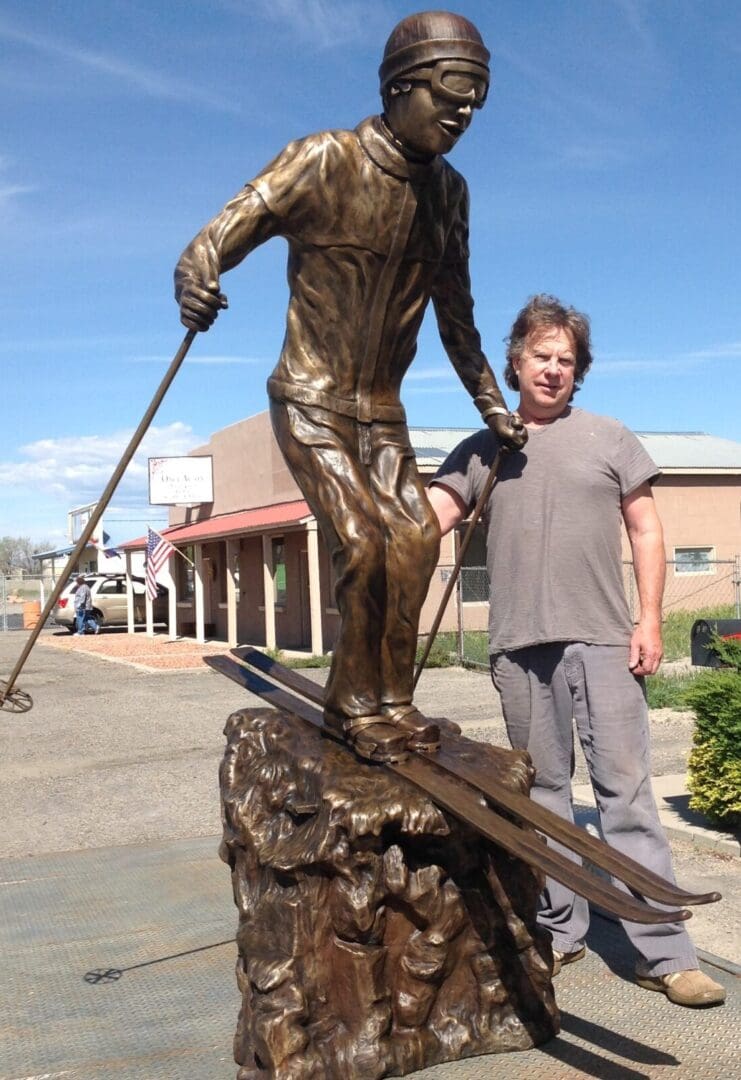 A man standing next to a statue of a skier.